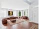 An open concept living room features a hardwood floor, large windows, leather furniture, and decorative rug at 1728 Callandale Ave, Cary, NC 27518