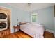 Comfortable bedroom with light blue walls, hardwood floors, and an adjacent laundry area at 1905 Bivins St, Durham, NC 27707