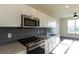 Modern kitchen with white cabinets, granite countertops, gray tile backsplash, and stainless steel appliances at 2226 Gathering Sq Ct, Fuquay Varina, NC 27526