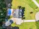 Aerial view of house with large driveway, backyard pool with lounge chairs and well-manicured lawn surrounded by greenery at 227 Paraggi Ct, Clayton, NC 27527