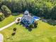 Expansive property with a beautiful blue house, well manicured lawn, pool, and detached garage surrounded by lush trees at 227 Paraggi Ct, Clayton, NC 27527