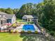 Aerial view of backyard pool with lush landscaping, pool house, back porch and black fencing at 227 Paraggi Ct, Clayton, NC 27527