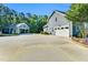 View of garage with parking, concrete driveway, and partial view of the blue home with landscaped greenery at 227 Paraggi Ct, Clayton, NC 27527