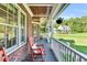 Covered porch with brick floor, a red rocking chair and brick detail work with nice view of the large manicured yard at 227 Paraggi Ct, Clayton, NC 27527