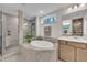 Luxurious bathroom with a large soaking tub, a walk-in shower, and neutral-toned tile and cabinets at 2721 Jazzy St, New Hill, NC 27562