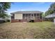 View of a home's backyard featuring a screened porch, lawn, and mature trees at 304 S Smith St, Clayton, NC 27520