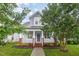 Charming two-story home featuring a covered porch, brick accents, a well-manicured lawn, and mature trees at 307 Millbrook Dr, Pittsboro, NC 27312