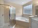 Bathroom with tiled shower, garden tub, and window at 3116 Kirby St, Durham, NC 27713