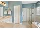 Well-lit bathroom features a glass-enclosed shower, soaking tub, and a vanity with white cabinets and countertop at 40 Breckenridge Pl, Dunn, NC 28334