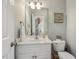 Well-appointed half-bathroom with a single sink vanity, toilet, and decorative mirror, conveniently located near staircase at 40 Breckenridge Pl, Dunn, NC 28334