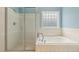 Clean bathroom featuring a glass shower, tub with jets, and a window, all surrounded by neutral tiling at 40 Breckenridge Pl, Dunn, NC 28334