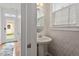 Cozy powder room with pedestal sink, round mirror, and patterned wallpaper at 4605 All Points View Way, Raleigh, NC 27614