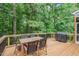 View of the deck with outdoor dining table and grill surrounded by lush trees at 5 Providence Ridge Ln, Durham, NC 27713