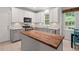 Kitchen with white cabinets, stainless appliances, and butcher block island illuminated by natural light from a large window at 5 Providence Ridge Ln, Durham, NC 27713