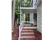 A covered porch with brick steps, white railings, and a cozy chair to enjoy the natural scenery at 516 Ryan Rd, Cary, NC 27511