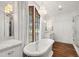 Luxurious bathroom featuring a soaking tub, chandelier, and a large window offering serene outdoor views at 523 Vick Ave, Raleigh, NC 27612