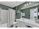 Well-lit bathroom with a shower-tub combo, white vanity, and stylish green walls at 533 Duchart Ln, Fuquay Varina, NC 27526