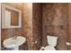 Bathroom with stylish accent wall, pedestal sink, toilet and glass shelving with brushed silver brackets at 5503 Silver Moon Ln, Raleigh, NC 27606