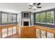 Bright living room featuring a corner fireplace, gleaming hardwood floors, and abundant natural light from multiple windows at 5503 Silver Moon Ln, Raleigh, NC 27606