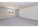 An empty bedroom with plush carpeting, neutral walls, and a large window overlooking the yard at 56 Braddock Ct, Garner, NC 27529