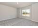 An empty bedroom with plush carpeting, neutral walls, and a large window for ample natural light at 56 Braddock Ct, Garner, NC 27529