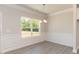 Dining area featuring decorative wainscoting, elegant lighting, and a large window at 56 Braddock Ct, Garner, NC 27529