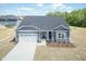 Charming single-story home featuring stone accents, gray siding, attached two-car garage, and professional landscaping at 56 Braddock Ct, Garner, NC 27529