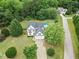 Aerial view of a white two-story home with a swimming pool in a wooded neighborhood at 5608 Scottish Hills Dr, Holly Springs, NC 27540