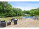 Wooden deck with an above-ground pool in the backyard surrounded by lush green trees for privacy and shade at 5608 Scottish Hills Dr, Holly Springs, NC 27540