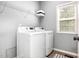 Bright laundry room featuring modern washer and dryer, wire shelving, and natural light from the window at 5637 Yates Garden Ln, Raleigh, NC 27606