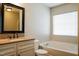 Well-lit bathroom with granite countertop, framed mirror, tub, and window at 6101 Ricker Rd, Raleigh, NC 27610