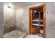 Bathroom with marble walls, stone floor, and access to a traditional wooden sauna at 6510 New Market Way, Raleigh, NC 27615
