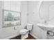 Cozy half bathroom featuring a pedestal sink, toilet, wood flooring, and a window providing natural light at 68 Holly Berry Ln, Durham, NC 27703