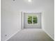Bright bedroom features neutral walls, plush carpeting, and a view from the window at 8621 Neuse Club Ln # 106, Raleigh, NC 27616