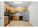 Well-lit kitchen featuring wood cabinetry, stainless steel refrigerator, and laminate flooring at 8621 Neuse Club Ln # 106, Raleigh, NC 27616