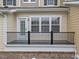 Covered patio area features black metal railing and a combination of brick and siding on the exterior at 9164 Wooden Rd, Raleigh, NC 27617