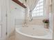 Soaking tub situated beneath a window with tiled surround and a shelf for decorative items or toiletries at 9808 Rainsong Dr, Wake Forest, NC 27587
