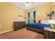 A cozy bedroom with hardwood furniture, a ceiling fan, and a window with blue curtains at 9808 Rainsong Dr, Wake Forest, NC 27587