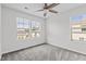 Well-lit bedroom with gray carpet, a ceiling fan and double windows at 1102 Latitude Dr, Durham, NC 27713