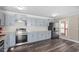 Well-lit kitchen with stainless steel appliances, light gray cabinets, and dark hardwood flooring at 111 Mcdole Cir, Cary, NC 27511