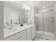 Modern bathroom with dual sinks, white countertops, gray tile, and a glass-enclosed shower at 1112 Prewitt Ranch Dr, Holly Springs, NC 27540