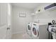 Neat laundry room with modern washer and dryer, plus storage shelves at 1112 Prewitt Ranch Dr, Holly Springs, NC 27540