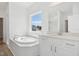 Bright bathroom features a white bathtub, granite countertop, and a window overlooking the yard at 112 Moonflower Ln # Homesite 267, Wilson's Mills, NC 27520