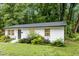 Charming, one story, white brick home, with black front door and mature trees at 117 Bertie Dr, Raleigh, NC 27610
