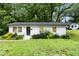 Charming, one story, white brick home, with black front door and green landscaping at 117 Bertie Dr, Raleigh, NC 27610