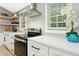 Bright kitchen features stainless steel appliances, herringbone backsplash and white cabinets at 117 Bertie Dr, Raleigh, NC 27610
