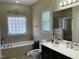 Bright bathroom featuring a soaking tub, glass-enclosed shower, and elegant vanity at 119 Hunterwood Pl, Benson, NC 27504