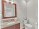 Elegant powder room with granite countertop, wood framed mirror, and a traditional toilet at 1237 Shirehall Park Ln, Wake Forest, NC 27587