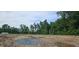 New home construction site shows the foundation, utilities, and a wooded lot under a blue sky at 145 Caspian Ct, Lillington, NC 27546