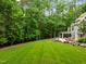 Expansive grassy backyard with landscaping, a stone patio, seating and a shed for storage at 1501 Chatsworth Ln, Raleigh, NC 27614